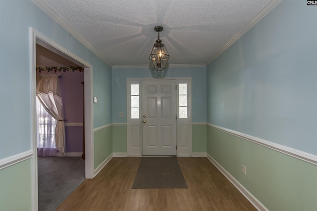 foyer with crown molding, a textured ceiling, baseboards, and wood finished floors