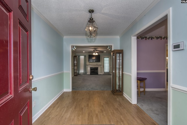 foyer featuring ornamental molding, light colored carpet, a fireplace, and a textured ceiling