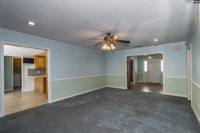 unfurnished living room featuring dark colored carpet, ornamental molding, and washer / dryer