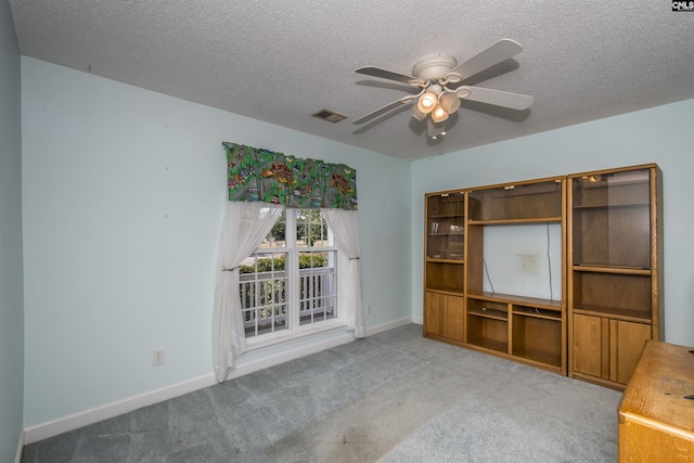 interior space featuring a textured ceiling, ceiling fan, carpet flooring, and baseboards