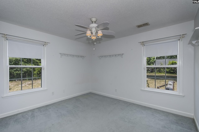 carpeted spare room with a textured ceiling, a ceiling fan, visible vents, and baseboards