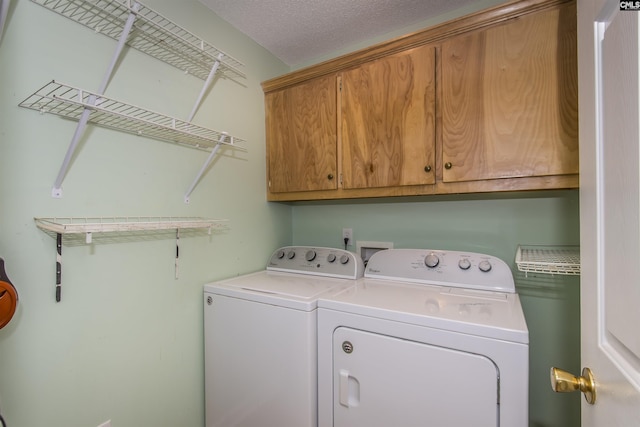 laundry area featuring washing machine and dryer, cabinet space, and a textured ceiling