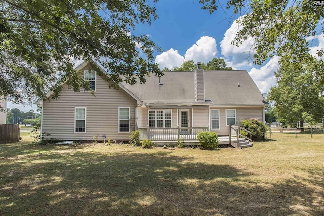 rear view of property with a yard, a chimney, fence, and a wooden deck