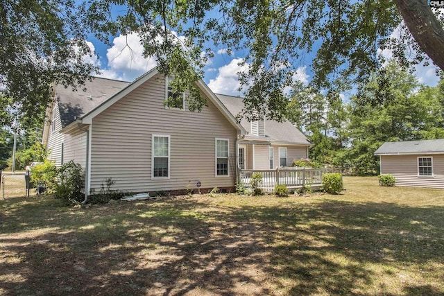 rear view of house featuring a yard, a wooden deck, and fence