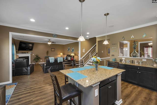 kitchen featuring a kitchen island, a kitchen breakfast bar, open floor plan, hanging light fixtures, and light stone countertops