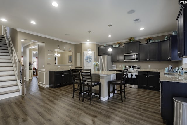 kitchen featuring a center island, decorative light fixtures, stainless steel appliances, a sink, and a kitchen bar