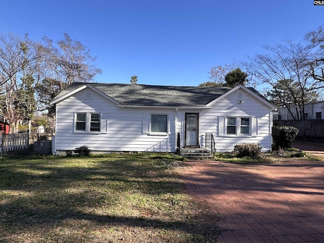 view of front of home with a front yard, roof with shingles, and fence