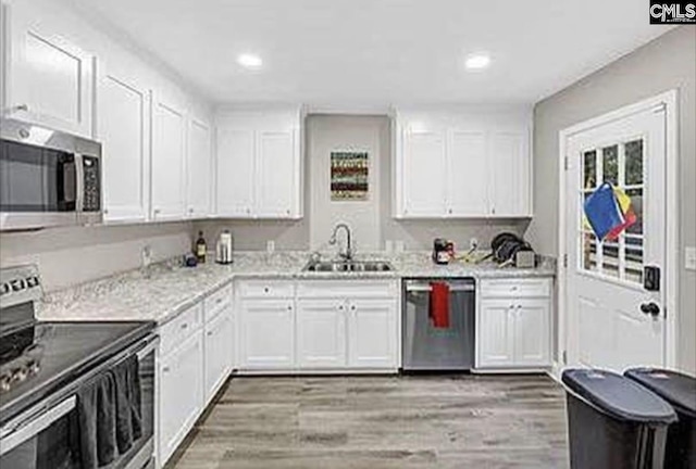 kitchen featuring appliances with stainless steel finishes, light wood-type flooring, white cabinetry, and a sink