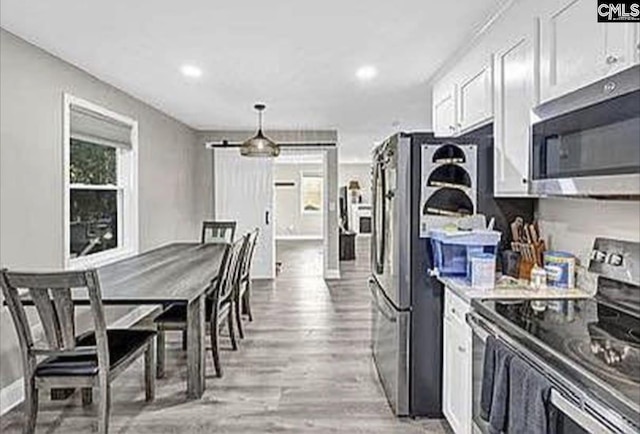 kitchen with white cabinets, a healthy amount of sunlight, light wood-type flooring, and stainless steel appliances