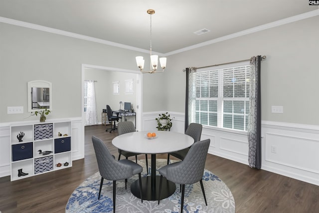 dining area with dark wood-type flooring, a chandelier, and ornamental molding