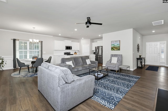 living room with visible vents, dark wood-style floors, ornamental molding, ceiling fan with notable chandelier, and recessed lighting