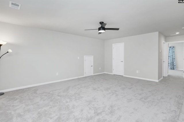 interior space with a ceiling fan, light colored carpet, visible vents, and baseboards