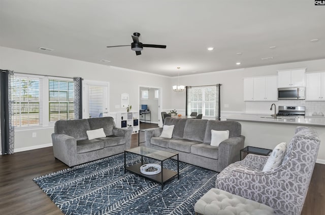 living room with recessed lighting, visible vents, dark wood-type flooring, baseboards, and ceiling fan with notable chandelier