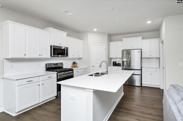 kitchen featuring stainless steel appliances, light countertops, white cabinetry, a sink, and an island with sink