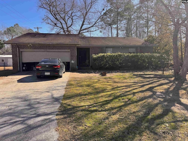 single story home featuring driveway, brick siding, an attached garage, and a front yard