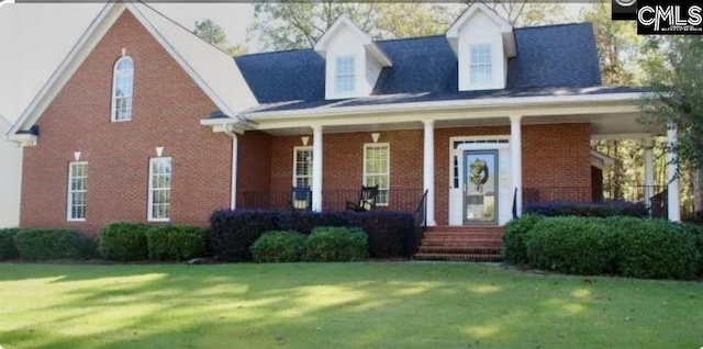 view of front of house with brick siding, covered porch, and a front yard