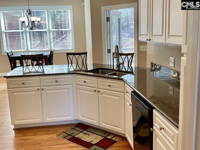 kitchen featuring hanging light fixtures, white cabinets, a sink, dark stone countertops, and dishwasher