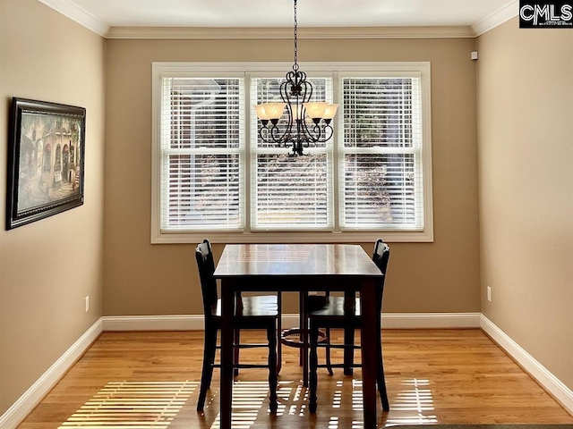 dining space with baseboards, ornamental molding, wood finished floors, and an inviting chandelier