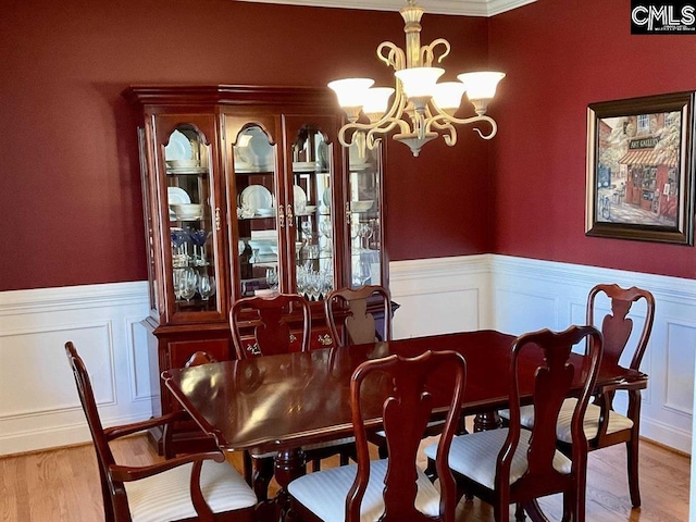 dining space featuring a wainscoted wall, a chandelier, and light wood-style floors