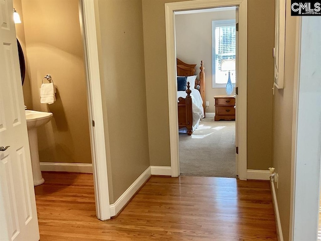 hallway featuring light wood-style floors, a sink, and baseboards