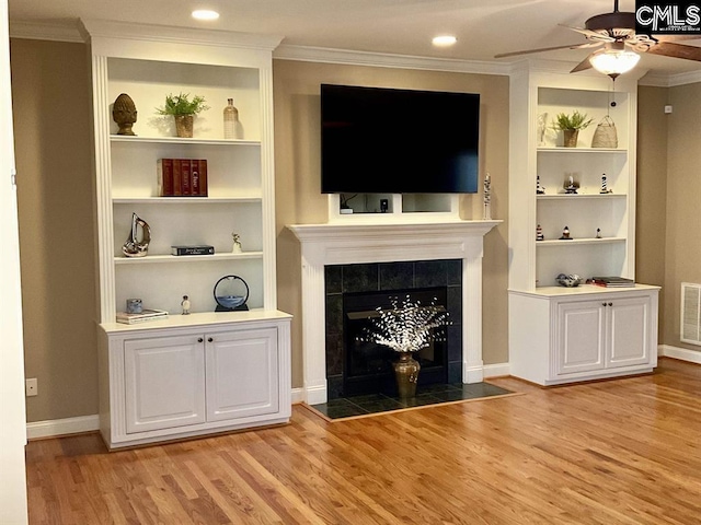 unfurnished living room featuring light wood-type flooring, a tile fireplace, visible vents, and crown molding