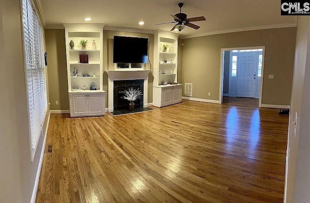 unfurnished living room with a fireplace with raised hearth, ornamental molding, and light wood-style flooring