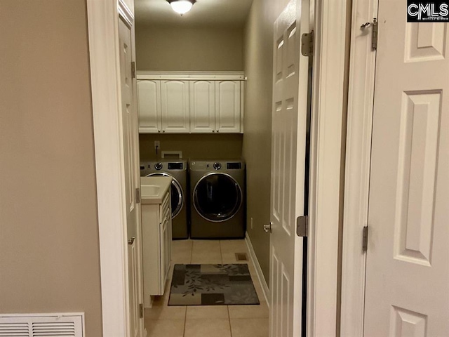 washroom featuring light tile patterned floors, visible vents, baseboards, cabinet space, and washer and clothes dryer