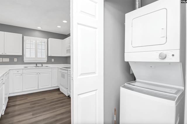 laundry room featuring recessed lighting, laundry area, dark wood-type flooring, a sink, and stacked washer and clothes dryer