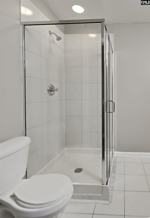 full bathroom featuring toilet, tile patterned flooring, a shower stall, and a textured ceiling