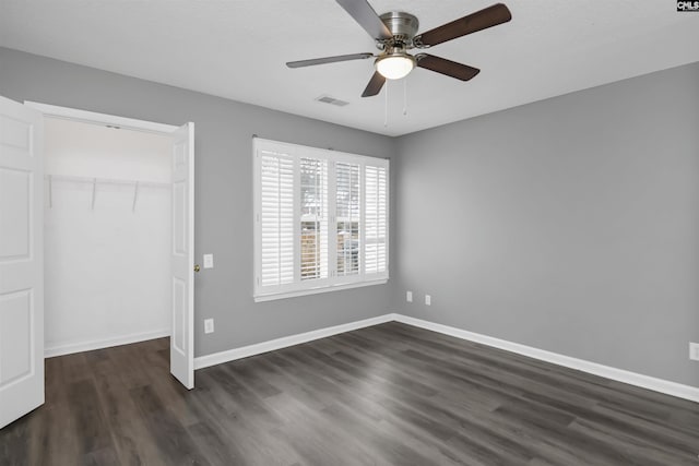 unfurnished bedroom with dark wood-type flooring, a closet, visible vents, and baseboards