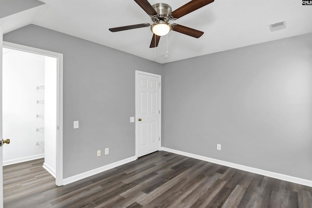 unfurnished bedroom with baseboards, visible vents, dark wood finished floors, a ceiling fan, and vaulted ceiling