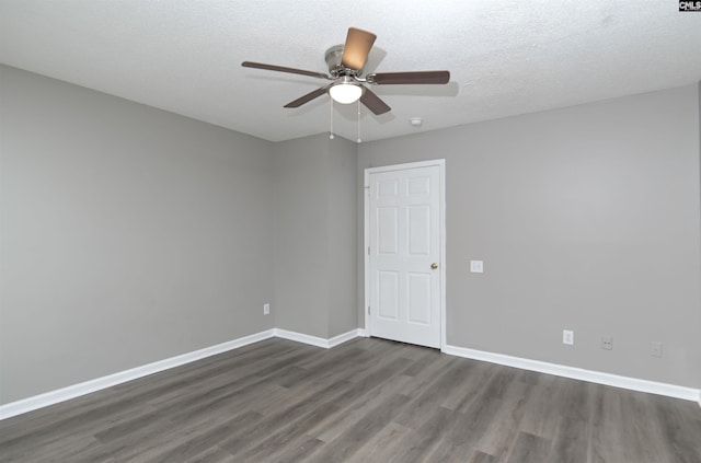 empty room with a ceiling fan, dark wood finished floors, a textured ceiling, and baseboards