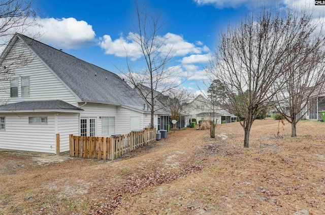 exterior space with roof with shingles and fence