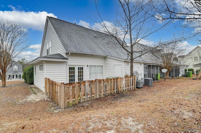 view of side of property with a shingled roof and fence