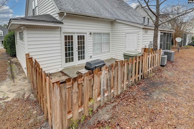 back of house featuring central AC unit, roof with shingles, fence, and french doors