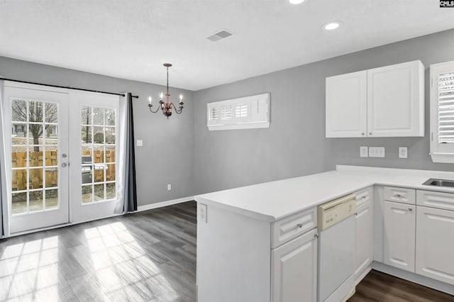 kitchen with white dishwasher, a peninsula, visible vents, white cabinets, and light countertops