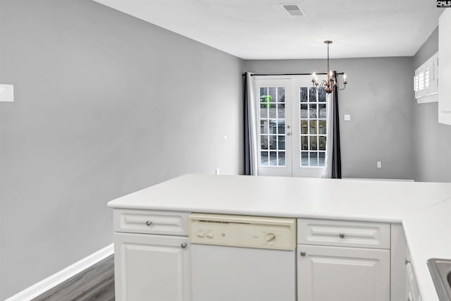 kitchen featuring white dishwasher, white cabinetry, light countertops, and decorative light fixtures