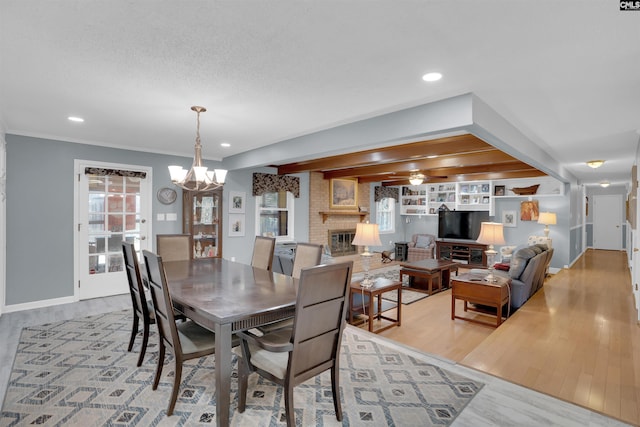 dining room featuring recessed lighting, a fireplace, a textured ceiling, and light wood finished floors