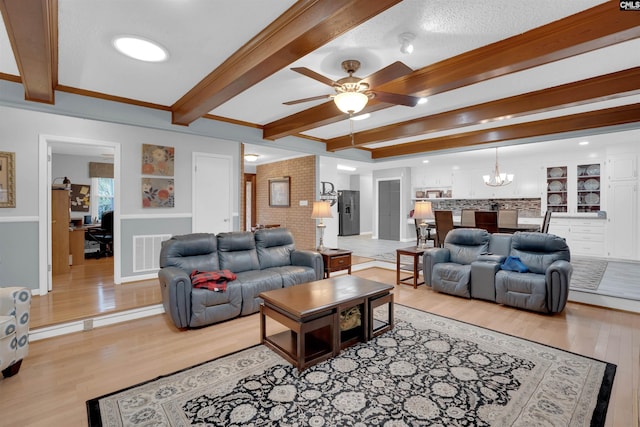 living area featuring ceiling fan with notable chandelier, beamed ceiling, light wood-type flooring, and visible vents