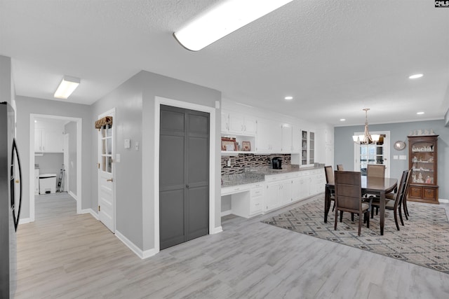 kitchen featuring white cabinets, light wood-type flooring, decorative backsplash, open shelves, and pendant lighting