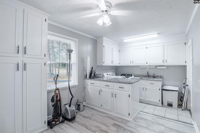 kitchen with light stone counters, crown molding, light wood-style floors, white cabinets, and ceiling fan