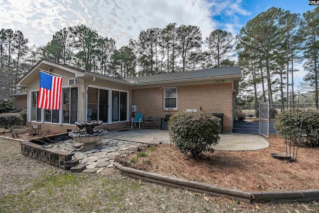 back of property featuring a sunroom, a patio area, and brick siding