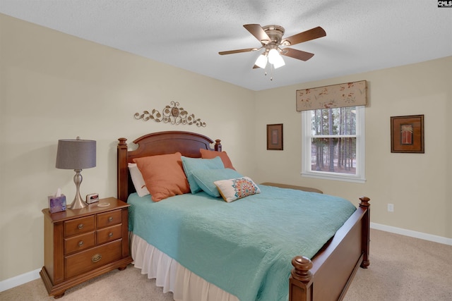 bedroom featuring light colored carpet, ceiling fan, a textured ceiling, and baseboards