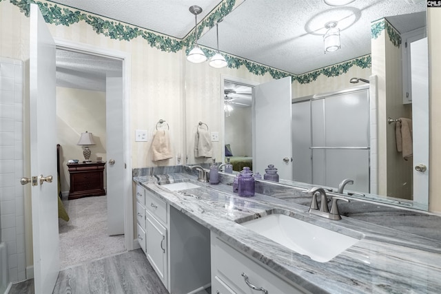 ensuite bathroom with a textured ceiling, a sink, and connected bathroom