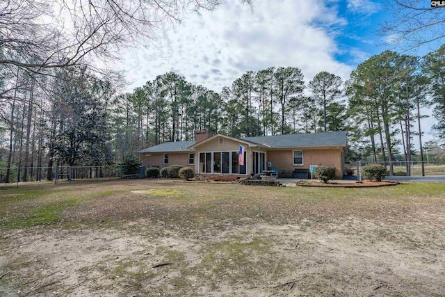 ranch-style house with brick siding, fence, a sunroom, a front lawn, and a chimney