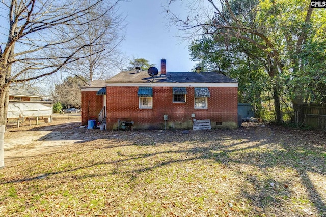 rear view of property with a chimney, crawl space, fence, a yard, and brick siding