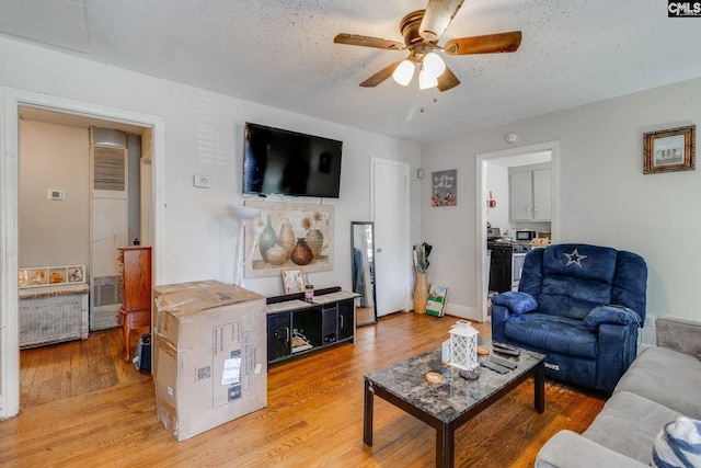 living area featuring a textured ceiling, ceiling fan, wood finished floors, and visible vents