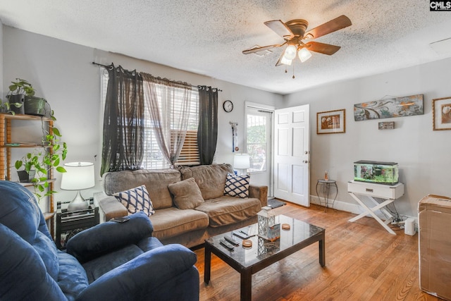 living area with light wood finished floors, a textured ceiling, baseboards, and a ceiling fan