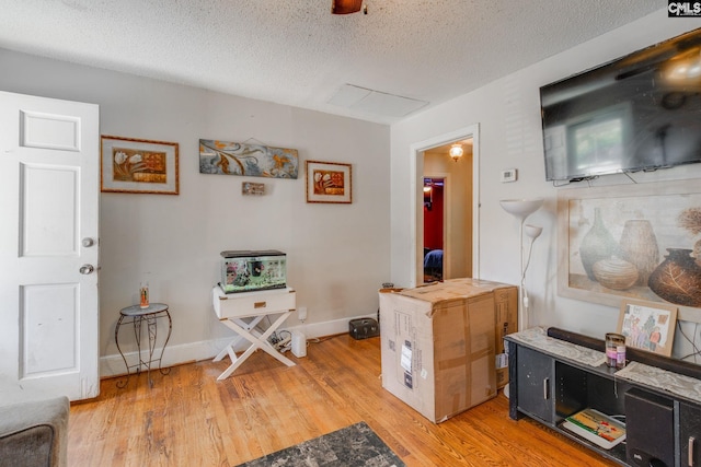 interior space with baseboards, a textured ceiling, and light wood finished floors