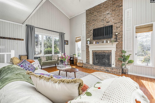 living area with high vaulted ceiling, plenty of natural light, a fireplace, and wood finished floors